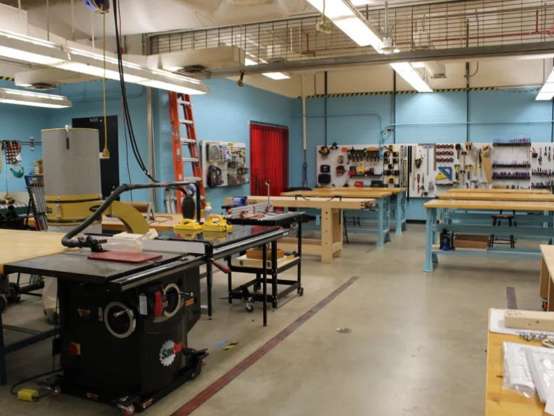 Large room with woodworking tables and tools mounted on the wall