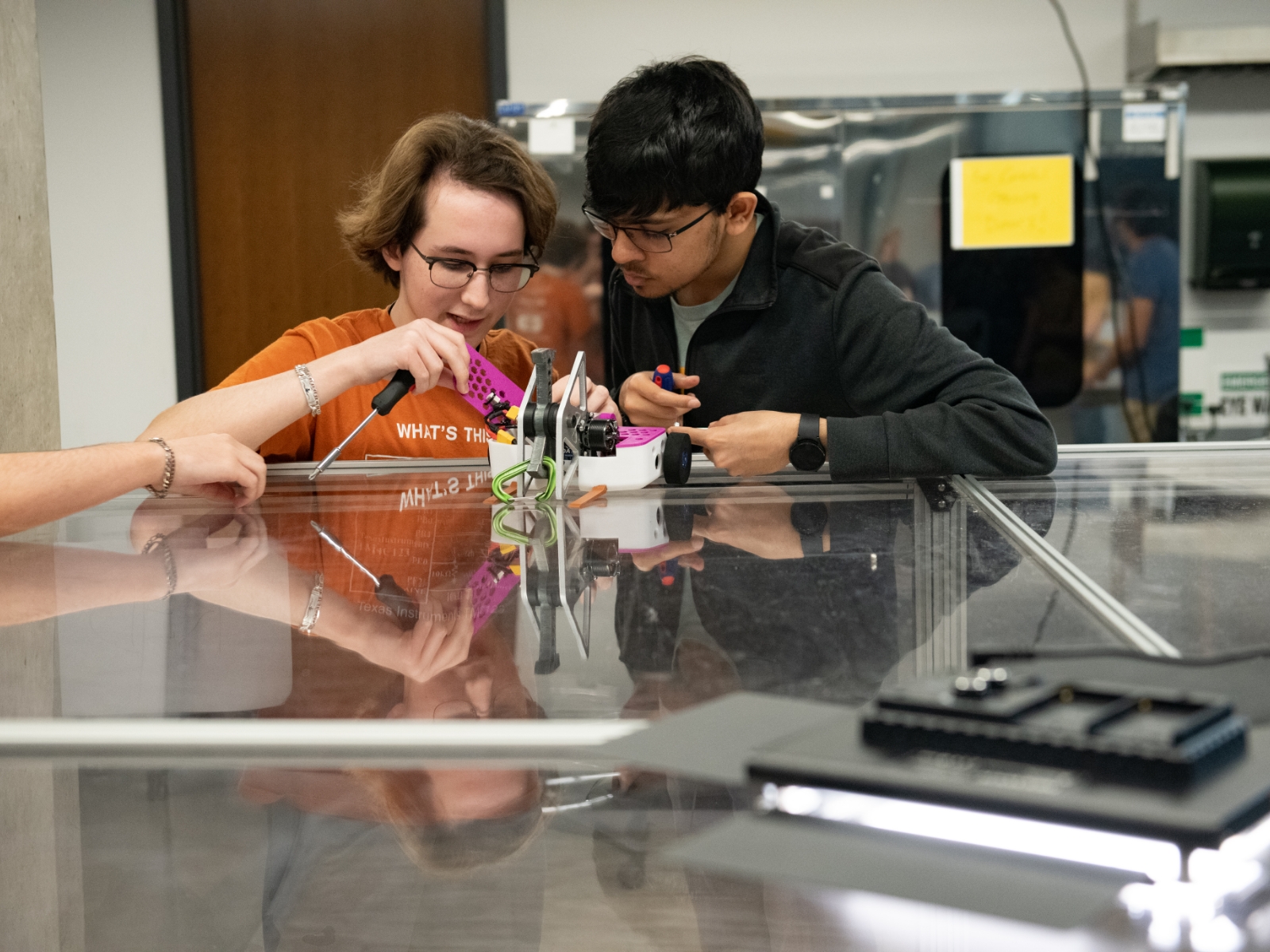 Two Texas engineering students working on a small robot