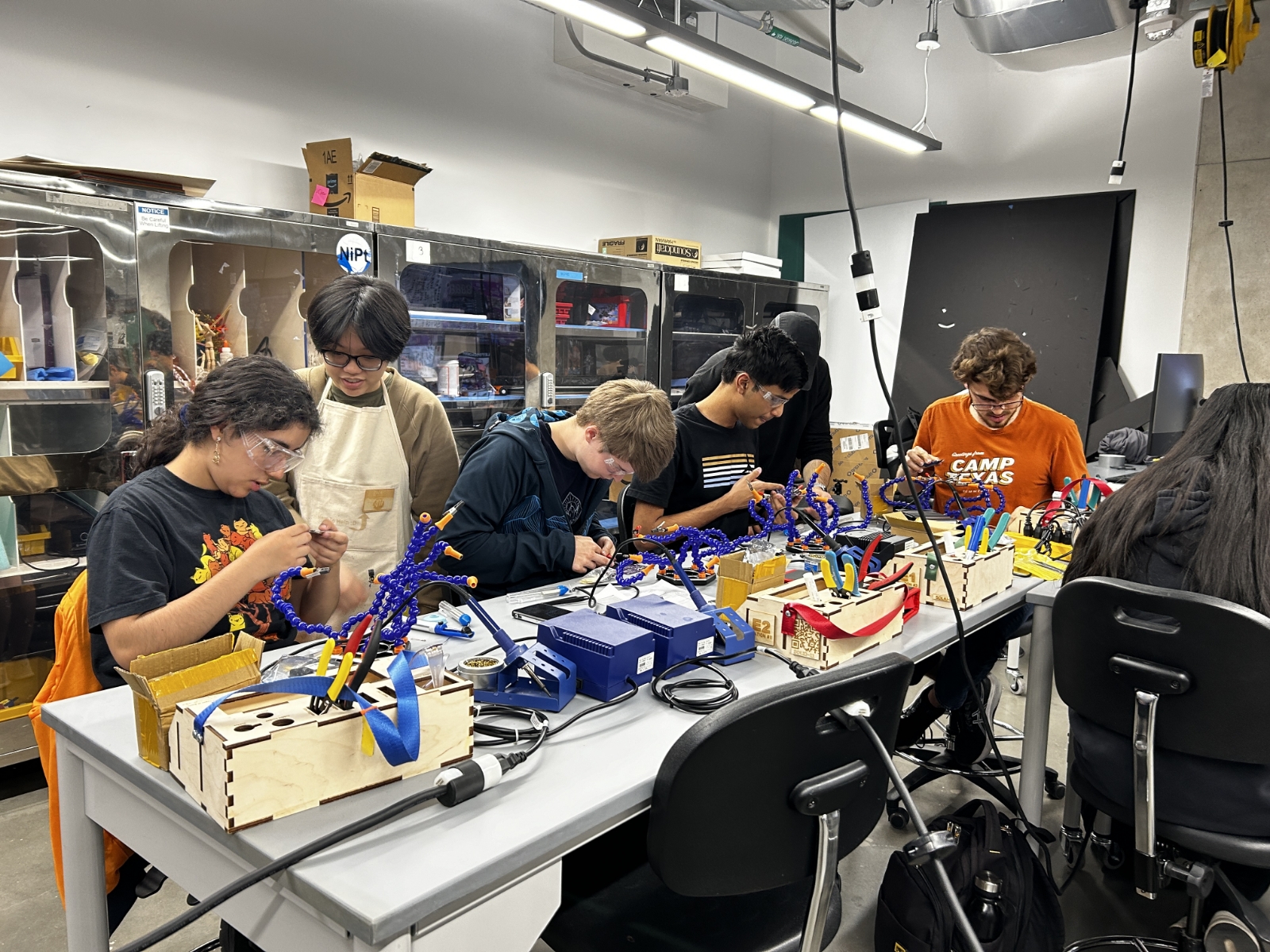 Texas engineering students at worktables creating with wires and wood materials